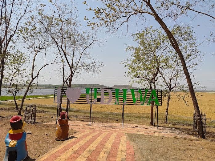 Green 'I love Udhwa' sign beside a brick walkway at the lakeside park